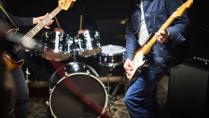 Guitarists playing in rehearsal studio equipped with drum kit and microphones