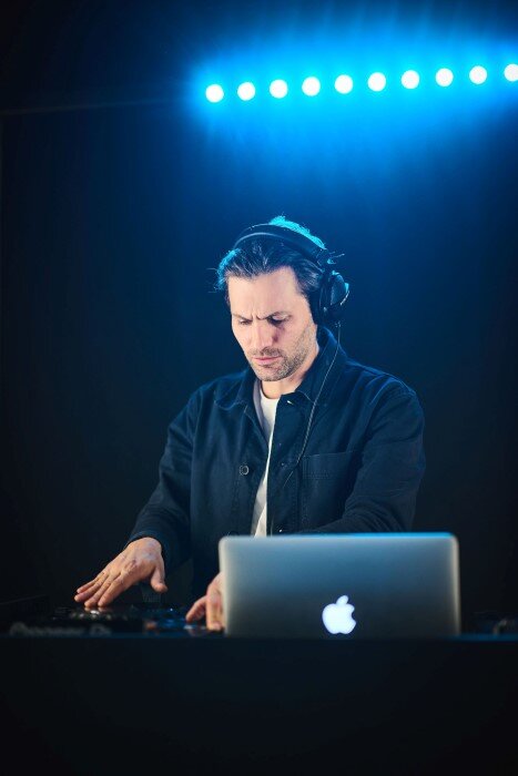 Male DJ mixing in studio, with headphones and lights