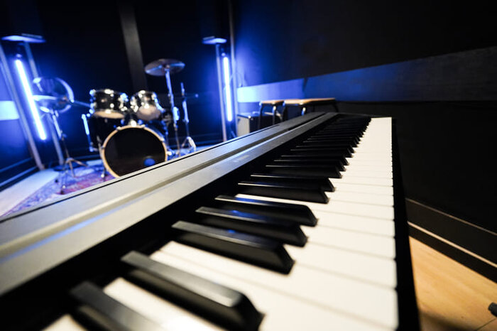 Yamaha P-145 piano in a rehearsal studio with drums in the background 