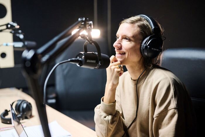 Podcaster in front of a Shure MV7 microphone with headphones on