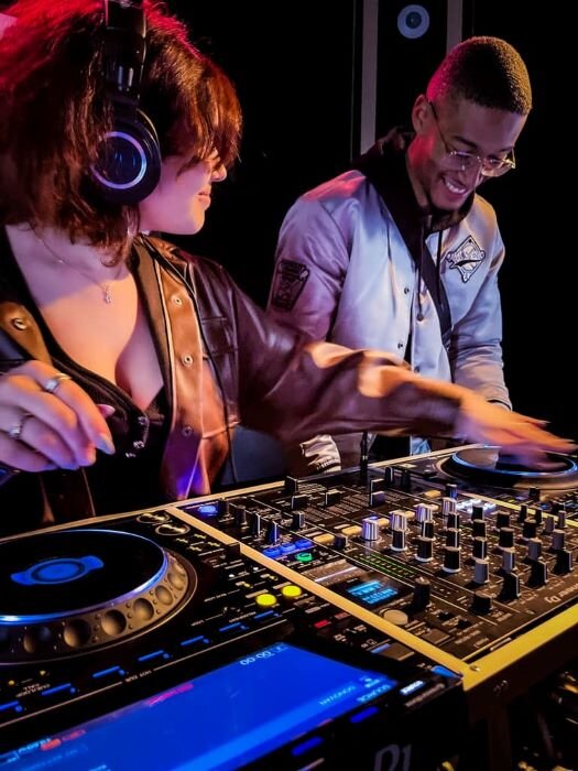 Woman and man in a DJ studio equipped with headphones and CDJ-3000