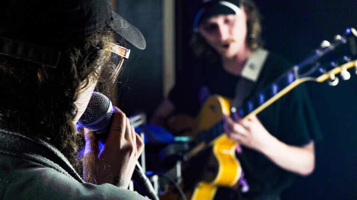 Young men singing and playing guitar in a rehearsal studio