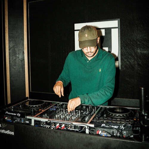 DJ avec un pull vert s'entrainant dans un studio DJ