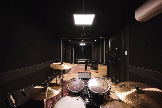 Studio de répétition avec batterie, amplis, et table de mixag