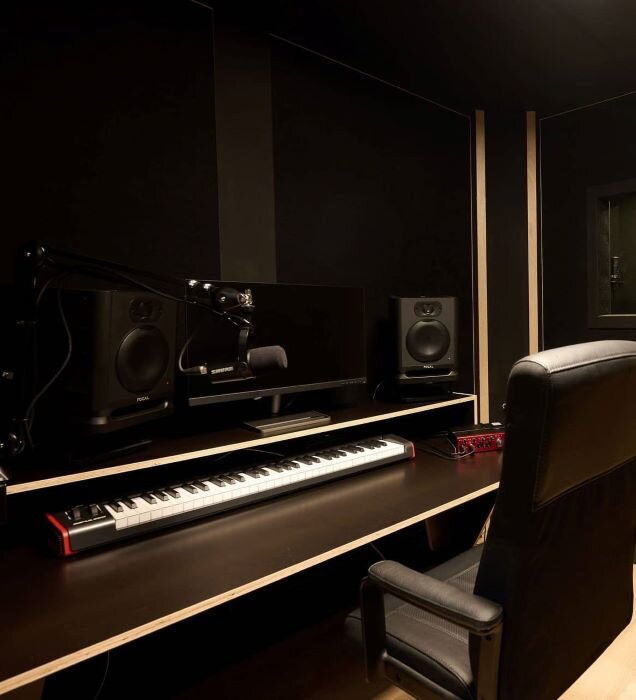 Recording studio with vocal booth, microphone, audio monitoring desk, and Focusrite sound card. | © Plug The Jack